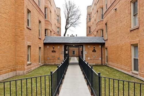 Front view of a brick apartment building with a central walkway entrance.
