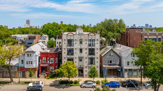 Front view of a four-story apartment building with a tiled facade, located between smaller residential buildings.