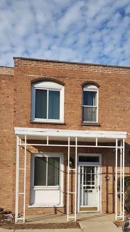 Front view of a two-story brick building with arched windows and a covered entryway.