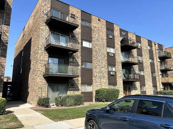 Front view of a multi-story brick apartment building with balconies.