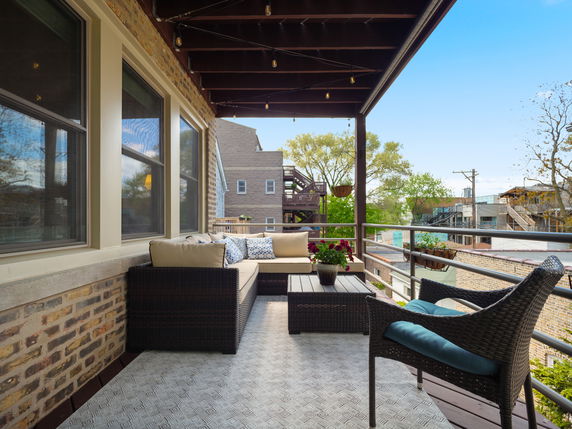 Outdoor seating area with furniture on a balcony overlooking surrounding buildings.