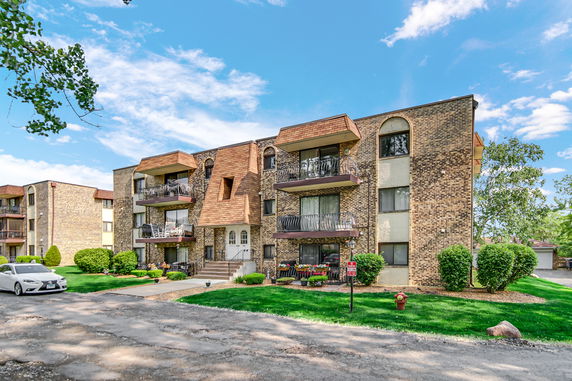 Front view of a multi-story apartment building with balconies and a brick exterior.