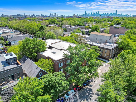 Wide-angle view of a residential area with trees and buildings, and a city skyline in the distance.