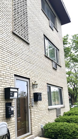 Front view of a multi-story brick building with large windows and a glass door.