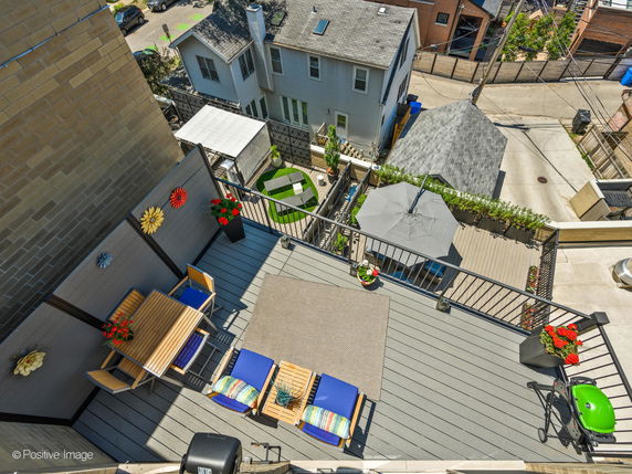 Rooftop with seating area and decorations, including chairs and a table, with view of surrounding residential buildings.