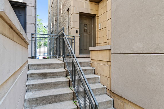Entrance to a building with concrete steps and metal railing.