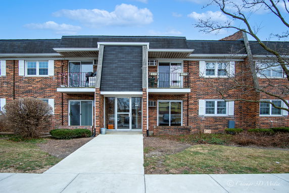 Front view of a two-story brick apartment building with balconies.