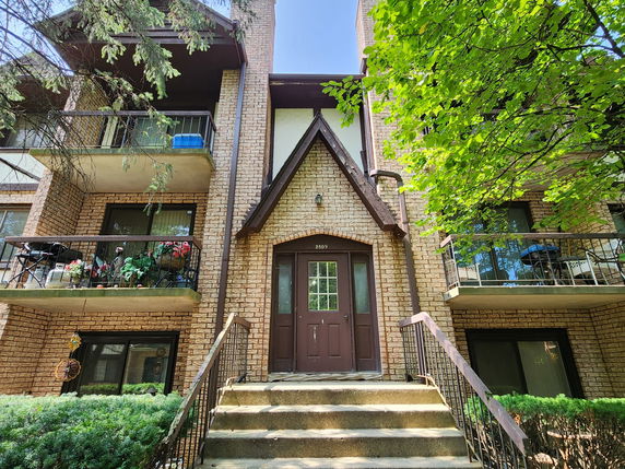 Front view of a multi-story brick building with balconies and a central entrance.