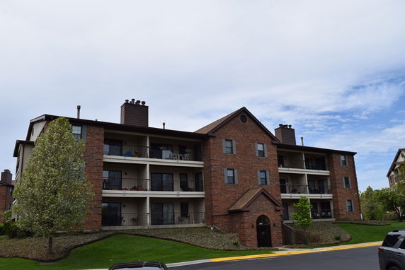 Front view of a multi-story brick apartment building with balconies.