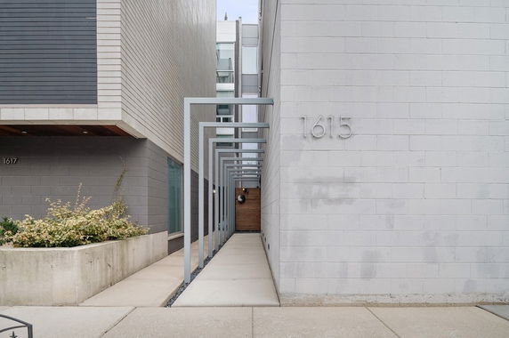 Front view of a modern building with a narrow walkway and architectural details.
