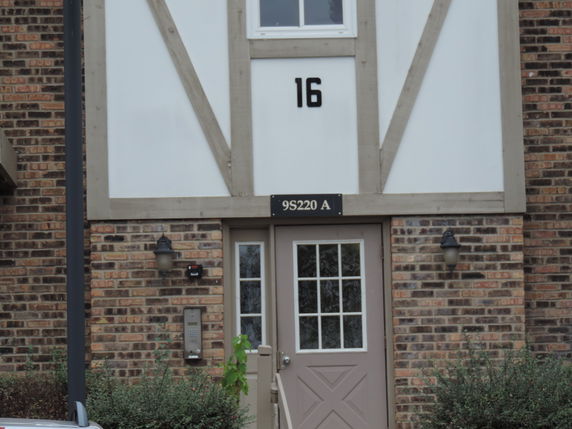 Front view of a brick building with a single door and the number 16 displayed above.