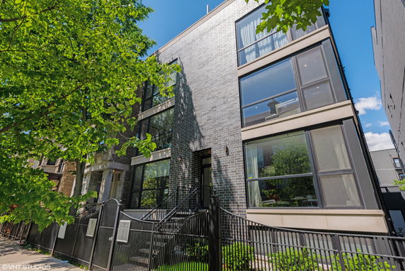 Front view of a modern multi-story building with large windows and a brick exterior.