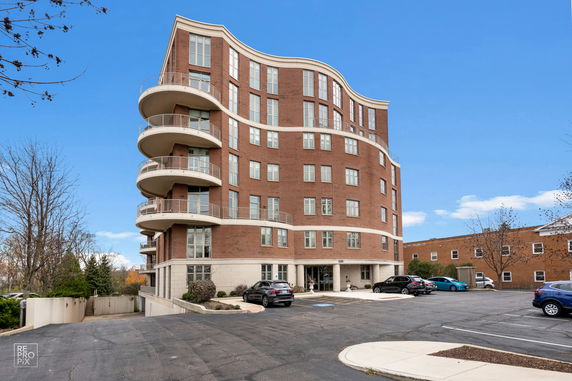 Front view of a multi-story building with curved balconies and brick facade.