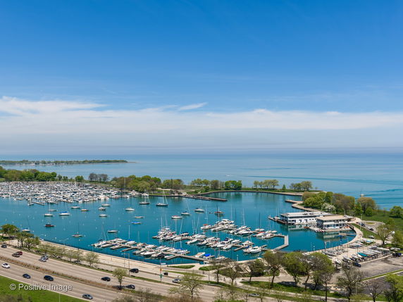 Aerial view of a marina with boats docked and a vast expanse of water in the background.