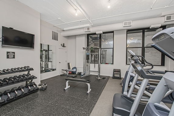 Indoor gym area with exercise machines, dumbbells, and a wall-mounted TV.