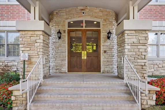 Front entrance of a building with stone walls and double wooden doors.