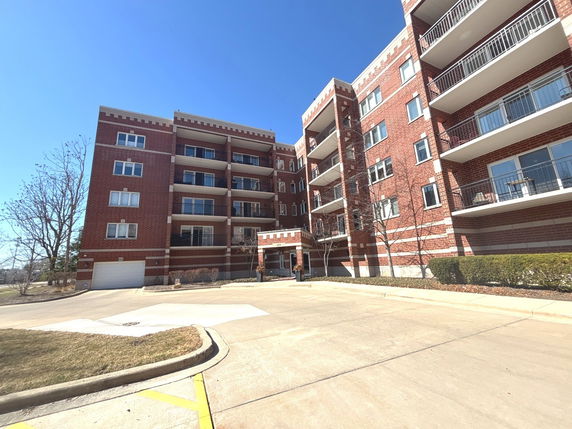 Front view of a multi-story brick apartment building with balconies.