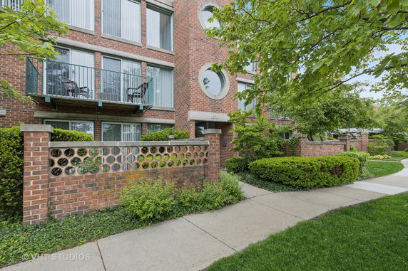 Front view of a multi-story brick apartment building with balconies.
