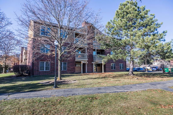 Front view of a three-story brick apartment building with balconies.