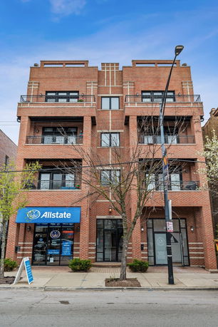 Front view of a multi-story brick building with balconies and a commercial storefront at street level.