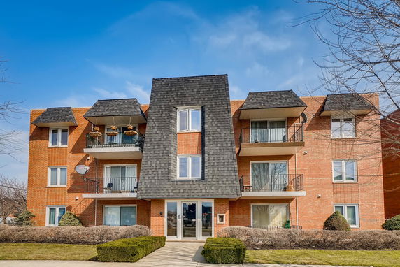Front view of a multi-story brick apartment building with balconies.