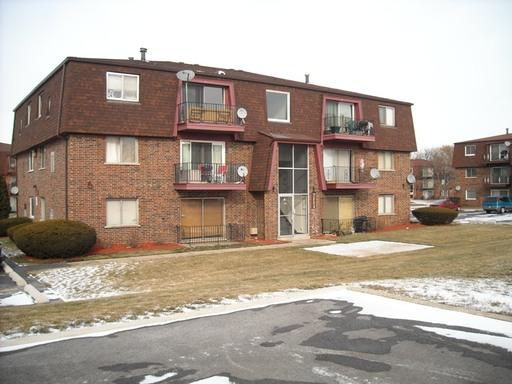 Front view of a multi-story apartment building with brick exterior and balconies.