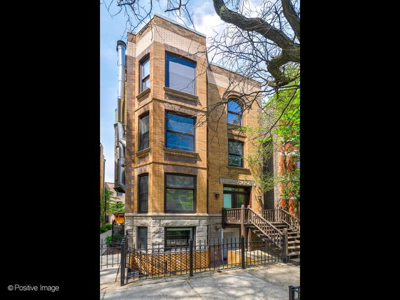 Front view of a multi-story brick building with large windows and a staircase leading to the entrance.