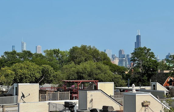 Panoramic view of a city skyline with trees and rooftops in the foreground.