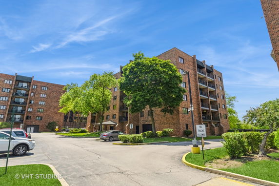 Front view of a multi-story brick apartment building with balconies.