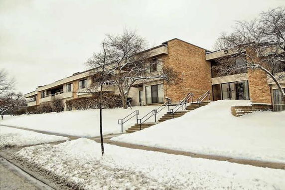 Front view of a multi-story brick building with snow-covered stairs and pathways.