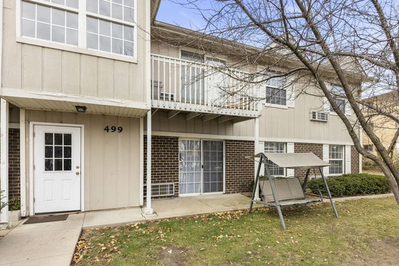 Front view of a two-story building with a balcony and a swing chair outside.