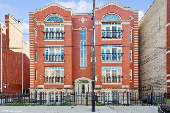 Front view of a multi-story red brick building with arched windows and iron balconies.