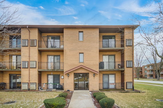 Front view of a three-story apartment building with balconies.