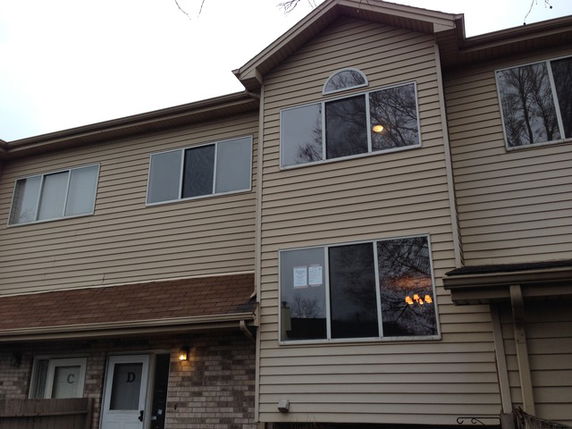 Front view of a two-story residential building with beige siding and multiple windows.