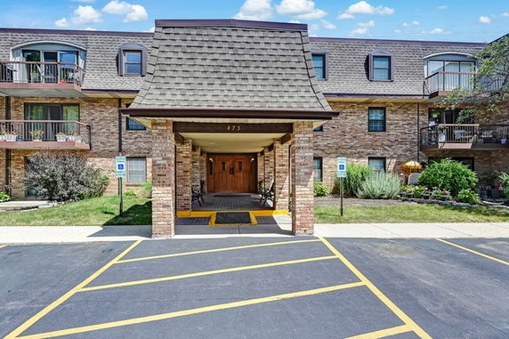 Front view of a multi-story brick apartment building with an entrance canopy.