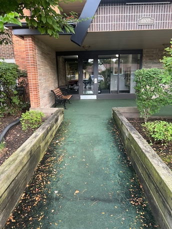 Front view of a building entrance with glass doors and surrounding shrubbery.