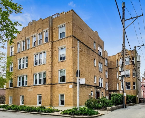 Front view of a multi-story brick building on a street corner.