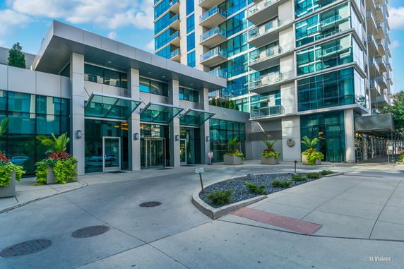 Front view of a modern multi-story building with large glass windows and balconies.