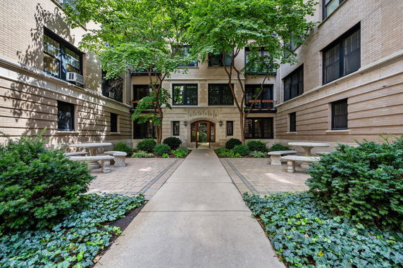 Front view of a multi-story brick building with landscaped garden and pathway.