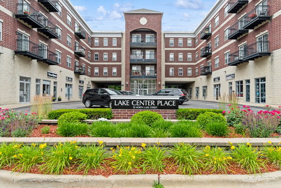 Front view of a multi-story brick building with parking and a sign reading 'Lake Center Place'.