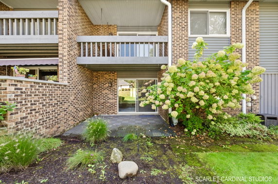 Front view of a brick building with balconies and a small patio.