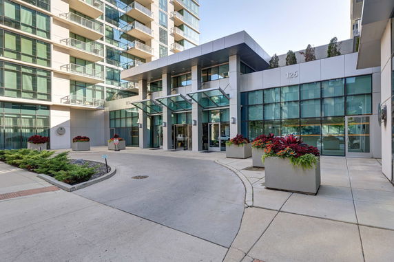 Front view of a modern apartment building with large glass windows and a covered entrance.