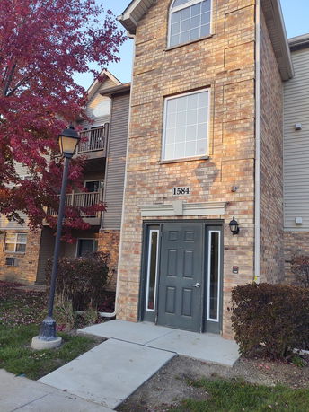 Front view of a three-story brick building with a central black door and large windows.