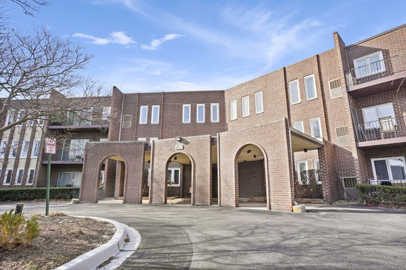 Front view of a multi-story brick building with arched entryways.