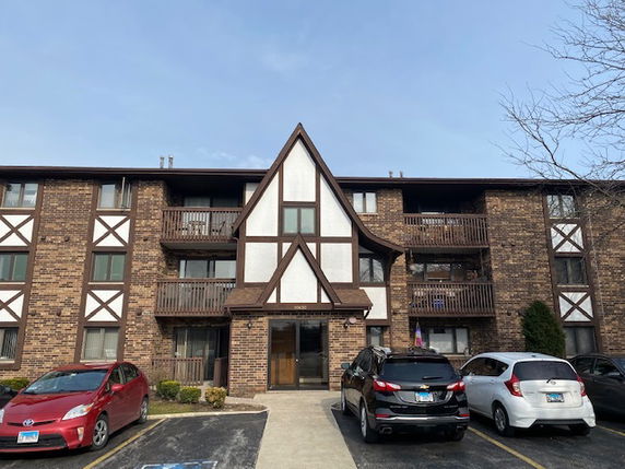 Front view of a multi-story brick apartment building with wooden balconies.