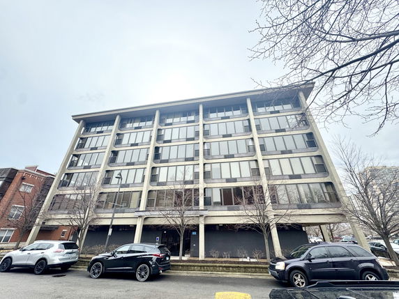 Front view of a multi-story commercial building with large windows and parking in front.