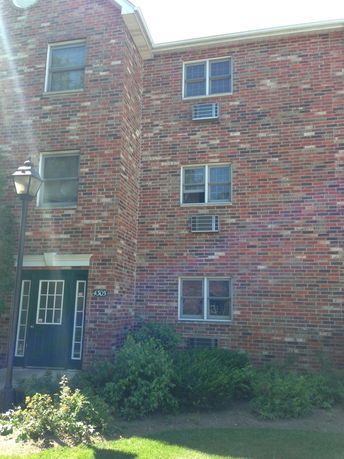 Front view of a brick apartment building with multiple windows and a green door.