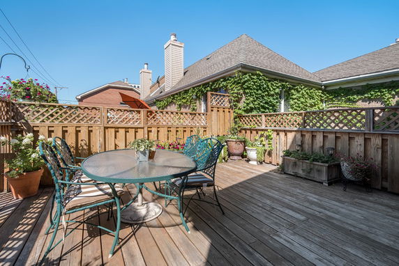 Rooftop deck with wooden flooring, outdoor furniture, and potted plants.