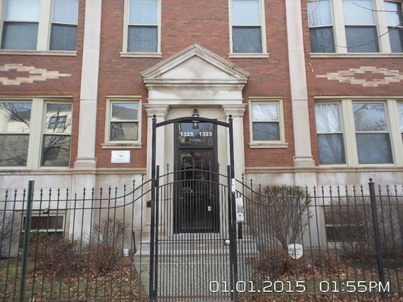 Front view of a multi-story brick building with a gated entrance.