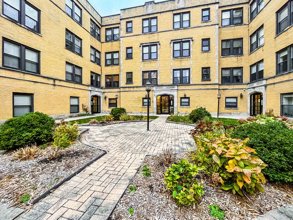 Front view of a multi-story apartment building with a central courtyard.